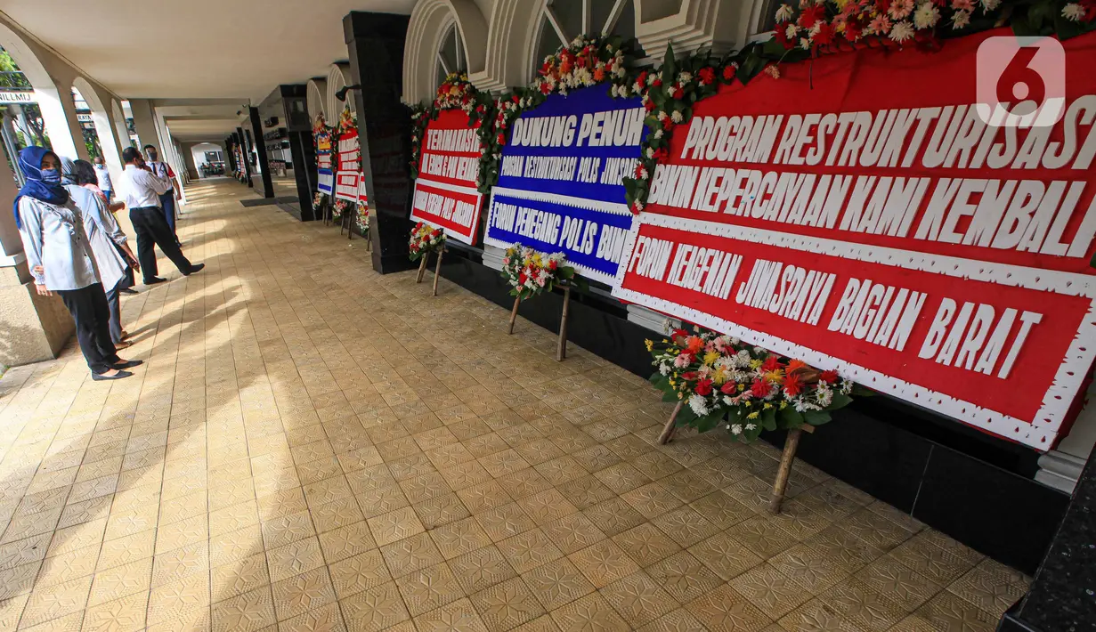 Seorang wanita melihat karangan bunga di halaman Kantor PT Asuransi Jiwasraya (Persero), Jakarta, Selasa (15/12/2020). Nasabah Jiwasraya ramai-ramai mengirimkan karangan bunga ke Kantor PT Asuransi Jiwasraya (Persero). (Liputan6.com/Faizal Fanani)