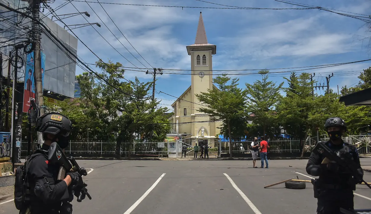Polisi berjaga di luar gereja setelah ledakan di Makassar (28/3/2021). Ledakan diduga bom terjadi di depan Gereja Katedral Makassar, Sulawesi Selatan pada Minggu (28/3/2021). (AFP/Indra Abriyanto)