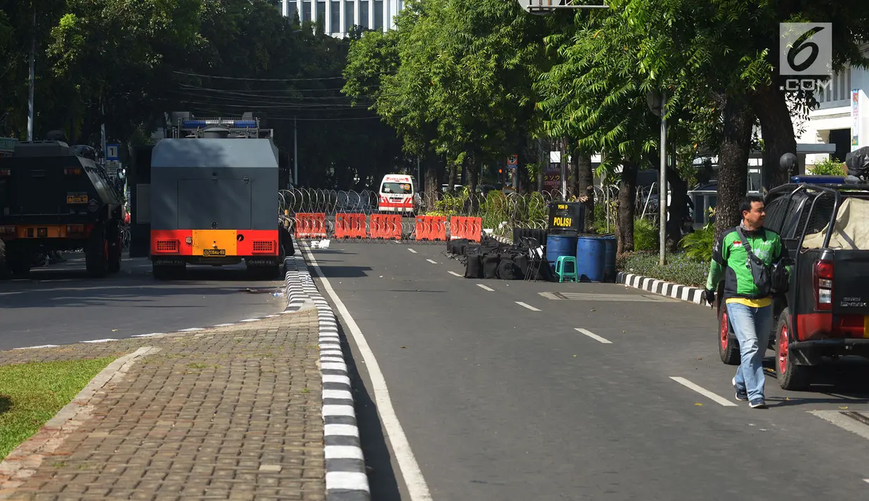 Pengemudi ojek online melintas dekat kendaraan taktis yang disiagakan di sekitar Gedung Mahkamah Konstitusi (MK), Jakarta, Kamis (27/6/2019). Rekayasa lalu lintas sudah disiapkan di sekitar gedung MK selama pelaksanaan sidang pembacaan putusan hasil sengketa pilpres 2019. (merdeka.com/Imam Buhori)