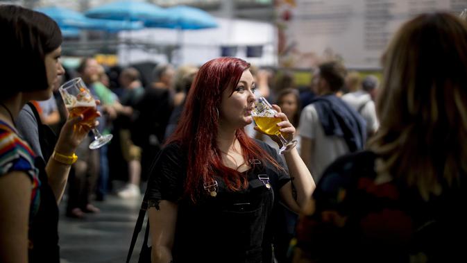 Seorang wanita menikmati minum bir selama The Great British Beer Festival di Kensington Olympia di London barat (6/8/2019). Great British Beer Festival tahunan ini diadakan 6-10 Agustus 2019. (AFP Photo/Tolga Akmen)