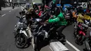 Sejumlah pengendara bergotong royong mengangkat sepeda motor mereka melewati pembatas jalan untuk berpindah jalur di kawasan Ridwan Rais, Jakarta, Rabu (21/8/2019). Pengendara motor tersebut berpindah jalur disebabkan tidak sabar menunggu kemacetan. (Liputan6.com/Johan Tallo)