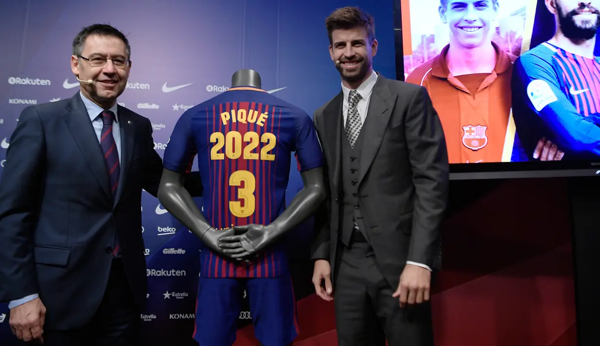 Bek Spanyol, Gerard Pique dan Presiden Barcelona FC, Josep Maria  berpose dengan jersey Barcelona pada pengumuman perpanjangan kontraknya di stadion Camp Nou, Senin (29/1). Pique memperpanjang kontraknya bersama Barcelona hingga 2022. (LLUIS GENE/AFP)