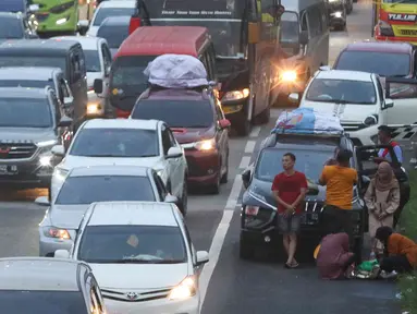 Pemudik beristirahat di tepian ruas jalan tol Cikopo-Palimanan, Jawa Barat, Kamis (28/4/2022). Ruas jalan tol yang mengalami peningkatan menyebabkan sebagian pemudik memilih untuk beristirahat di tepi jalan tol meski hal tersebut melanggar pertaturan yang berlaku. (Liputan6.com/Herman Zakharia)