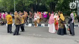 Sejumlah tamu menunggu kedatangan bus yang akan mengangkut mereka menuju resepsi pernikahan putra bungsu Presiden Jokowi, Kaesang Pangarep dan Erina Gudono dari Stadion Manahan, Solo, Jawa Tengah, Minggu (11/12/2022). Setelah turun dari bus, para tamu langsung berjalan kaki menuju tempat pengecekan tamu undangan di sebelah barat pintu masuk Pura Mangkunegaran. (Liputan6.com/Herman Zakharia)