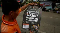 Seorang warga membaca poster yang dibagikan oleh KPU saat sosialisasi Pilkada DKI 2017 di Terminal Senen, Jakarta, Minggu (18/12). Sosialisasi pesta demokrasi ini guna mencegah banyaknya pemilih yang golongan putih atau golput. (Liputan6.com/Johan Tallo)