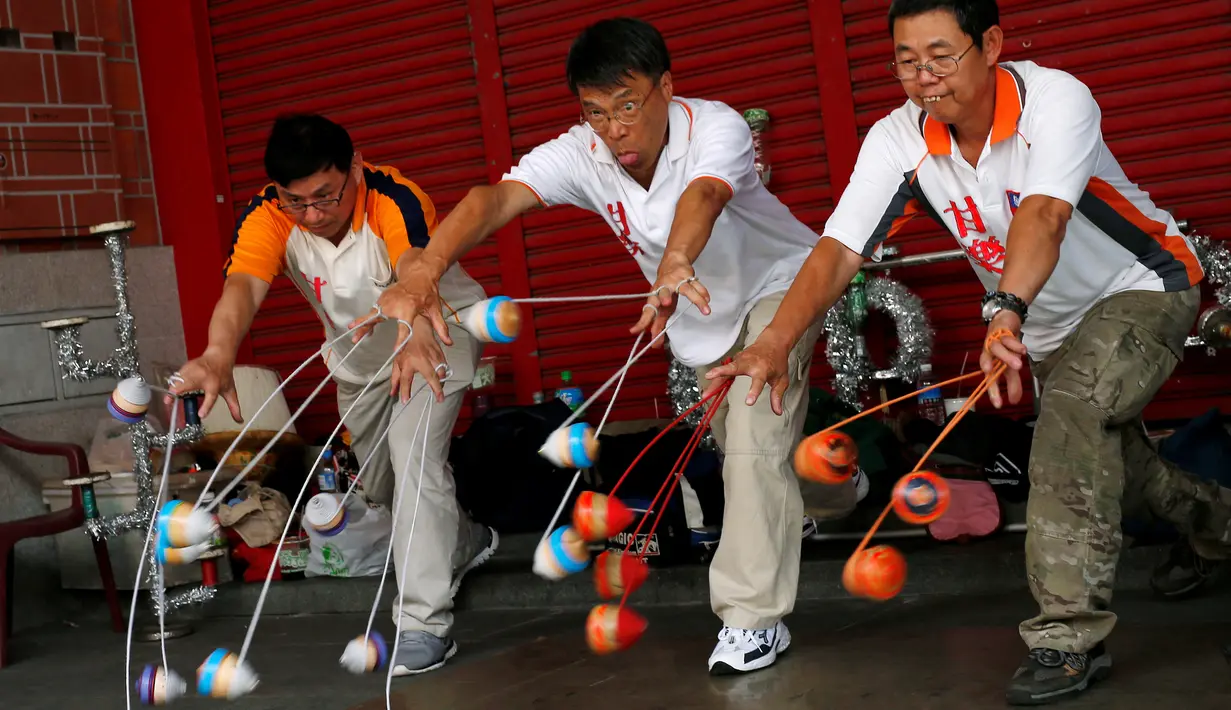 Sekelompok pakar gasing memainkan 18 gasing sekaligus saat turnamen gasing di New Taipei City, Taiwan (9/5). Dalam turnamen ini peserta menampilkan sejumlah trik mengagumkan. (REUTERS/Tyrone Siu)