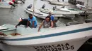 Para nelayan mendorong perahu mereka dari Teluk Meksiko menuju pinggir jalan di pelabuhan kota Veracruz, Rabu (9/8). Meksiko bersiap untuk menghadapi kedatangan Franklin, yang berubah menjadi badai dengan Kategori 1. (AP/Felix Marquez)