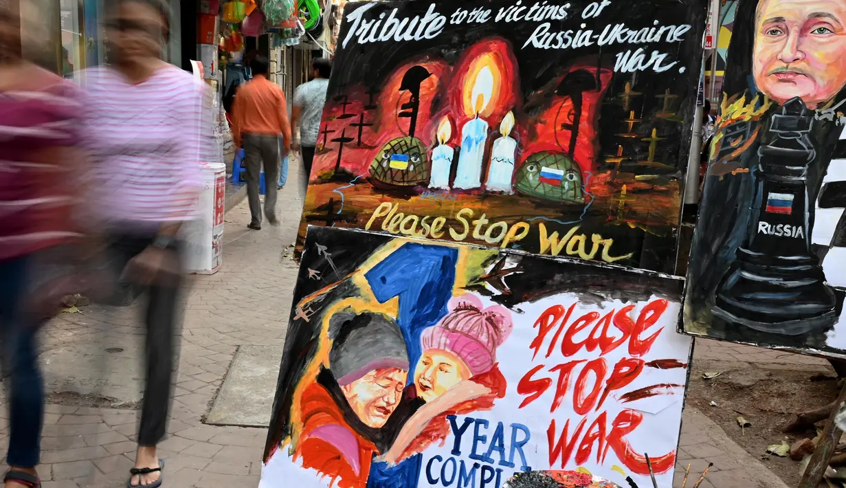 Para pejalan kaki berjalan melewati lukisan untuk memberikan penghormatan kepada para korban perang pada malam peringatan satu tahun invasi Rusia ke Ukraina, di Mumbai, India, Kamis 23 Februari 2023. Invasi Rusia ke Ukraina merupakan salah satu yang terbesar di Eropa sejak Perang Dunia II, ratusan ribu jiwa menjadi korban di kedua pihak, serta menciptakan krisis pengungsi terbesar di Eropa. (Punit PARANJPE/AFP)