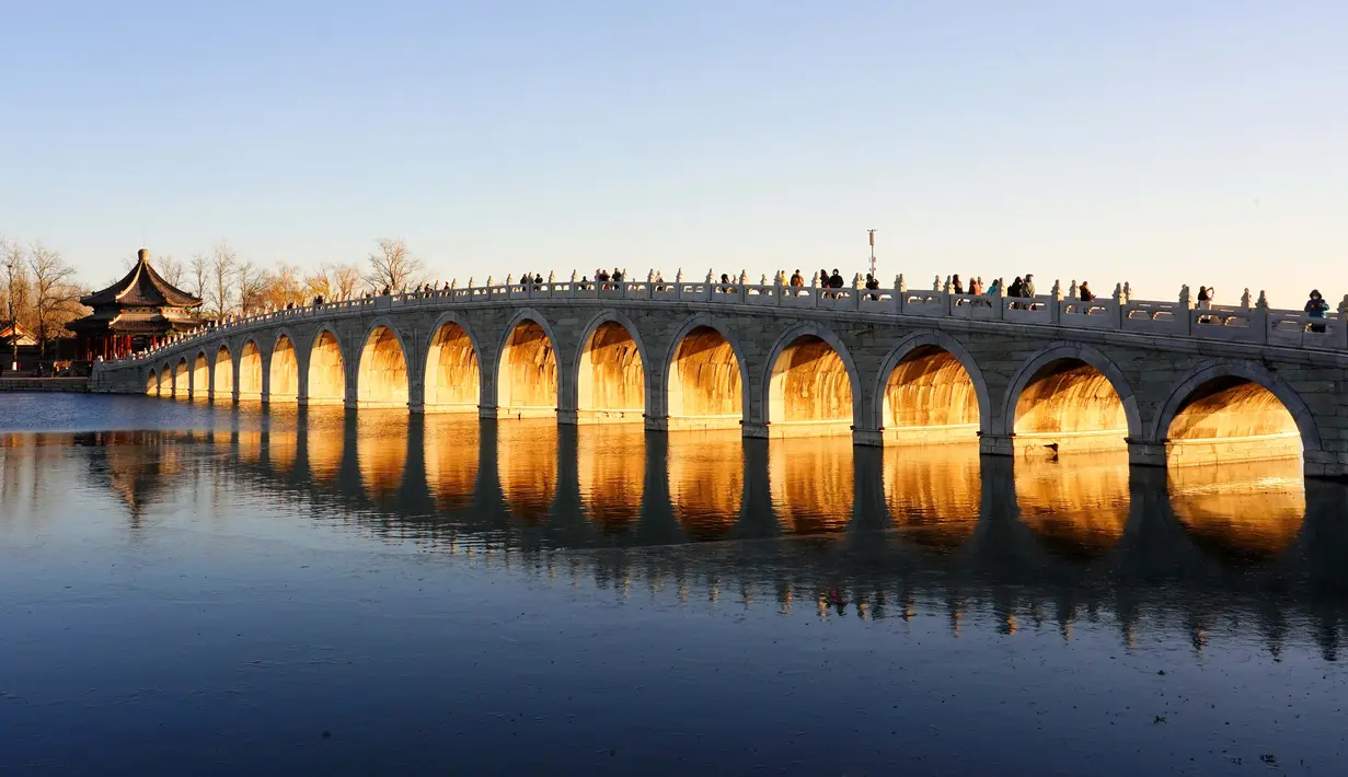Foto yang diabadikan pada 4 Desember 2020 ini menunjukkan matahari terbenam yang menyinari Jembatan 17 Lengkung di Istana Musim Panas di Beijing, ibu kota China. (Xinhua/Chen Jianli)