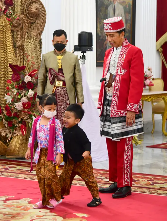 Presiden Joko Widodo (Jokowi) ditemani cucunya, Sedah Mirah dan Panembahan Al Nahyan Nasution pada Upacara Peringatan Detik-Detik Proklamasi Kemerdekaan ke-77 Republik Indonesia di Istana Merdeka, Jakarta, Rabu (17/8/2022). Sementara itu, Panembahan Al Nahyan tampak memakai atasan beskap hitam dan celana panjang batik berwarna cokelat. (Foto: Muchlis Jr - Biro Pers Sekretariat Presiden)