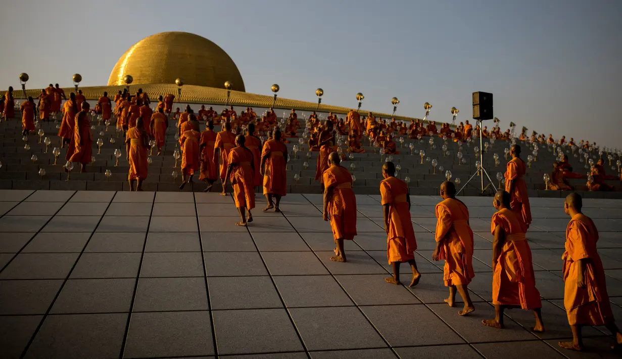 Para biksu Buddha bersiap untuk mengambil tempat sebelum beribadah pada perayaan Makha Bucha, di Wat Dhammakaya, utara Bangkok, Jumat (26/2/2021). Dalam perayaan tersebut, ada satu pantangan yang harus dilakukan, yakni larangan menjual minuman beralkohol selama satu hari penuh. (Jack TAYLOR/AFP)