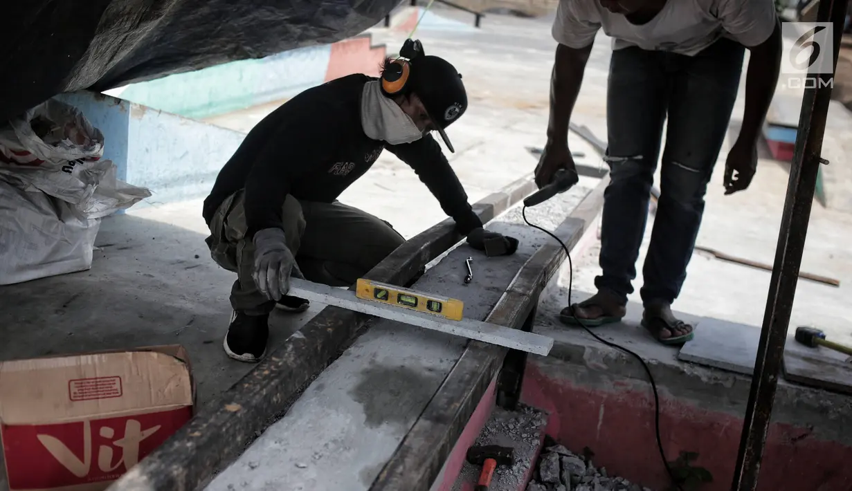 Pekerja memperbaiki arena skateboard yang rusak di RPTRA Kalijodo, Jakarta, Kamis (24/1). Perbaikan dilakukan untuk membuat rasa aman dan nyaman pengunjung yang menggunakan arena tersebut. (Liputan6.com/Faizal Fanani)