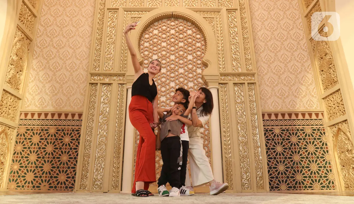 Pengunjung berswafoto saat melihat-lihat instalasi Istana Alhambra di Mal Senayan City, Jakarta Pusat, Kamis (15/4/2022). Instalasi megah setinggi 14 meter itu merupakan perwujudan dari tema The Divine Ramadan yang dibuat untuk menyemarakkan bulan puasa. (Liputan6.com/Herman Zakharia)