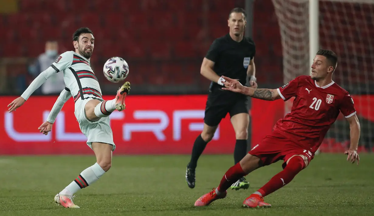 Gelandang Portugal, Bruno Fernandes (kiri) mengontrol bla di depan gelandang Serbia, Sergej Milinkovic-Savic dalam laga Kualifikasi Piala Dunia 2022 Zona Eropa Grup A di Rajko Mitic Stadum, Belgrade, Sabtu (27/3/2021). Portugal bermain imbang 2-2 dengan Serbia. (AFP/Pedja Milosavljevic)