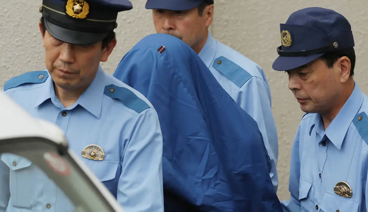 Satoshi Uematsu saat digelandang petegas di kantor polisi Tsukui, Sagamihara, Prefektur Kanagawa, Jepang, Rabu (27/7). Satoshi dengan menggunakan pisau membunuh setidaknya 19 orang dan melukai 26 lainnya. (AFP PHOTO/Jiji Press)