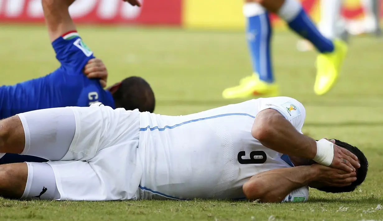 Luis Suarez (kanan) dan Giorgio Chiellini tergeletak usai beradu kontak untuk merebut bola, Brasil, Selasa (24/6/14). (REUTERS/Tony Gentile)