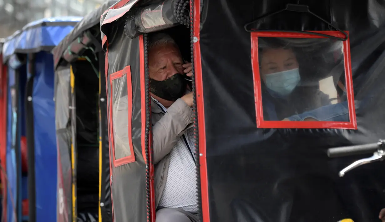 Orang-orang menggunakan bicitaxis setelah penghancuran beberapa stasiun layanan publik di Bogota (24/5/2021). Secara resmi, 43 orang tewas dalam bentrokan sejak protes menentang reformasi pajak yang diusulkan yang telah ditarik. (AFP/ Raul Arboleda)