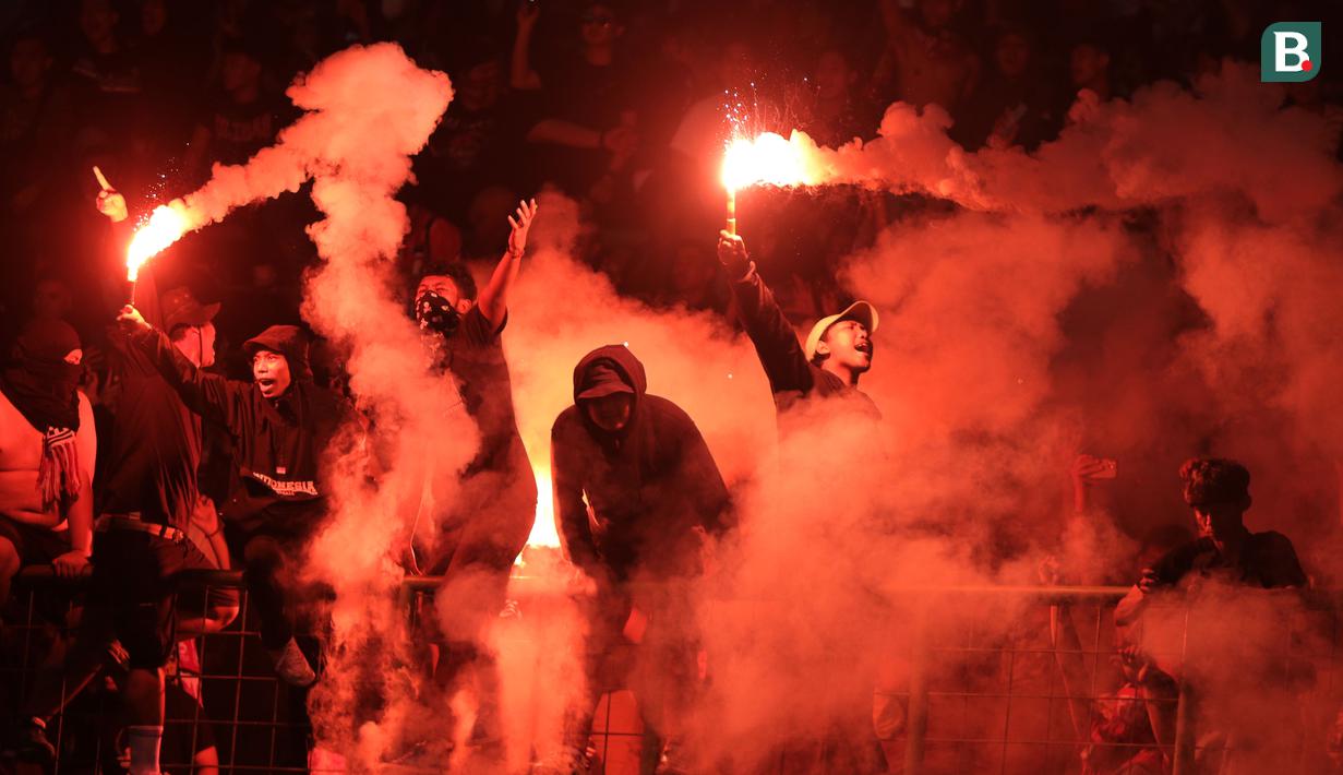 <p>Suporter Timnas Indonesia U-19 menyalakan suar saat laga Grup A Piala AFF U-19 2022 antara Timnas Indonesia U-19 melawan Timnas Vietnam U-19 di Stadion Patriot Candrabhaga, Bekasi, Jawa Barat, Sabtu (02/07/2022). (Bola.com/Ikhwan Yanuar)</p>