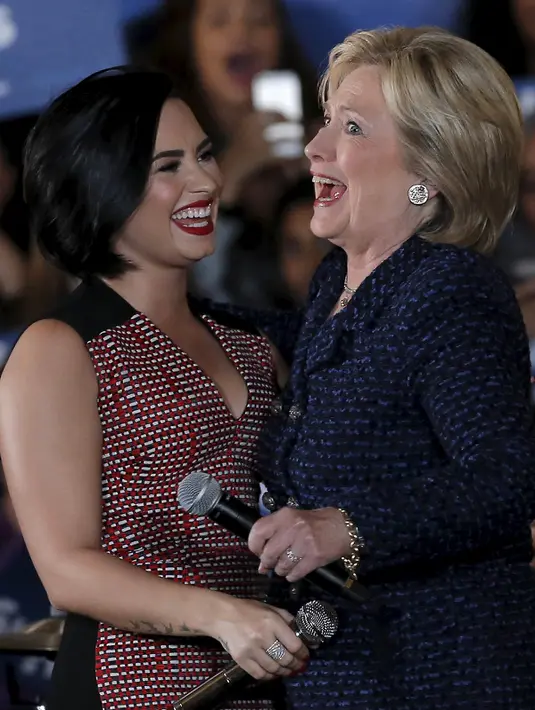Calon presiden AS dari Partai Demokrat Hillary Clinton tertawa dengan penyanyi Demi Lovato saat acara kampanye di Iowa City, Amerika Serikat, (21/). Hillary menjadi satu-satunya perempuan yang mencalonkan diri menjadi Presiden AS. (REUTERS/Jim Muda)