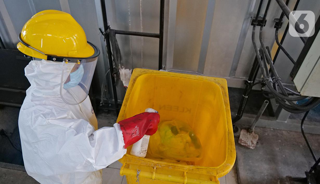 Petugas membersihkan tempat sampah dengan cairan disinfektan usai melakukan proses pembakaran limbah medis ke dalam incinerator di RSCM Jakarta, Jumat (26/6/2020). Volume limbah medis infeksius di seluruh Indonesia hingga 8 Juni 2020 mencapai lebih dari 1.100 ton. (Liputan6.com/Herman Zakharia)