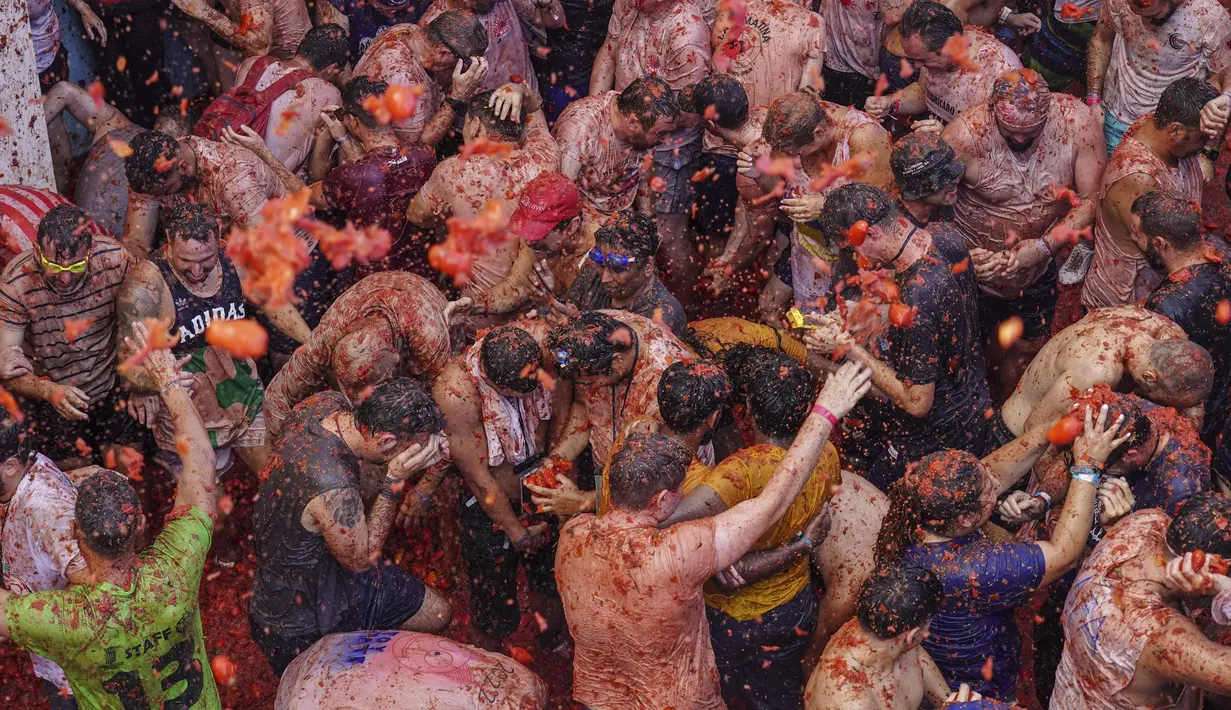 Orang-orang yang bersuka ria saling melempar tomat dalam acara tahunan "Tomatina", pesta pertarungan tomat di desa Bunol dekat Valencia, Spanyol, Rabu (31/8/2022). Seperti namanya, ratusan ton tomat disediakan untuk senjata dalam acara perang tomat. (AP Photo/Alberto Saiz)