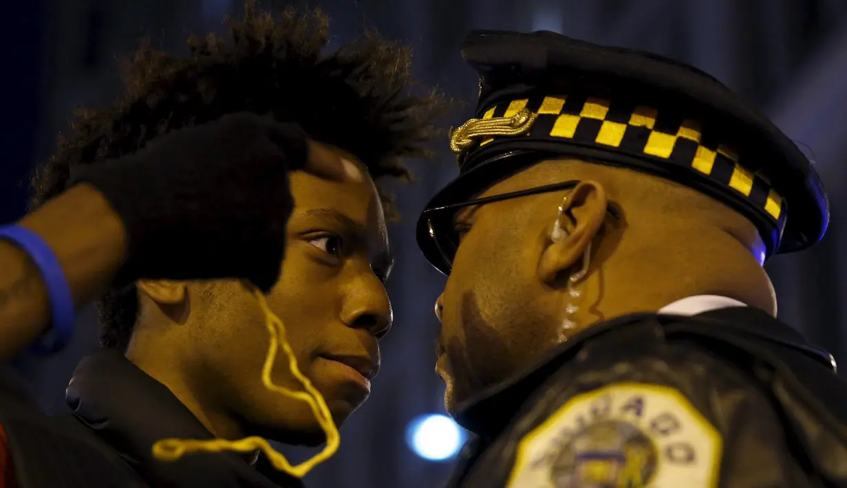 Massa bersitegang dengan polisi saat aksi protes di Chicago, Illinois, Rabu (25/11). Ketegangan rasial memanas setelah rilisnya video seorang polisi kulit putih menembak remaja kulit hitam, Laquan McDonald (17) pada Oktober 2014. (REUTERS/Andrew Nelles)