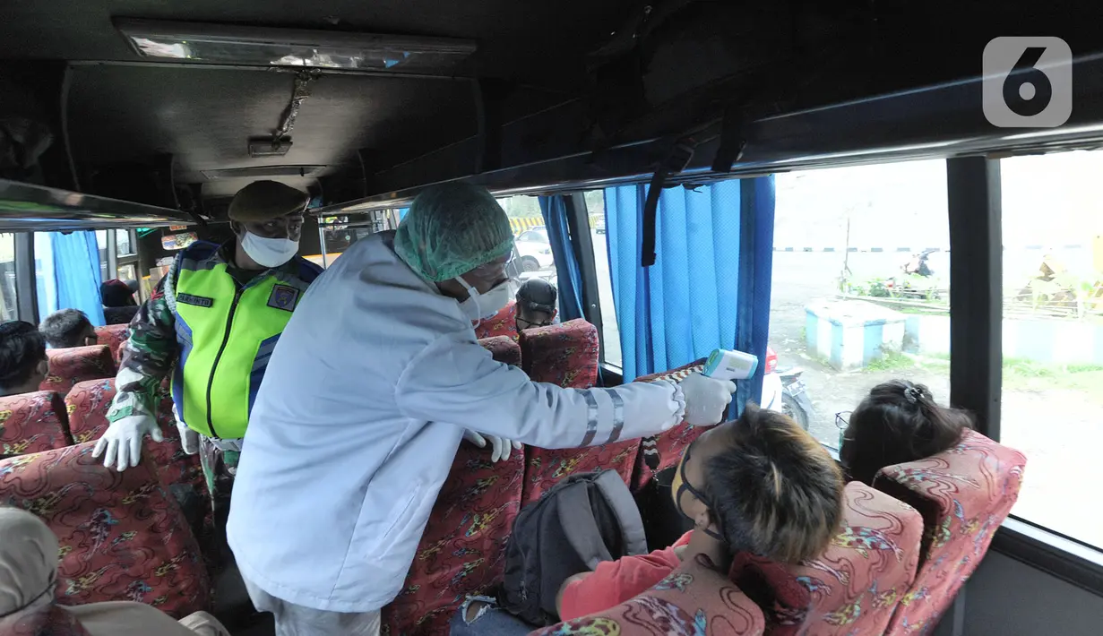 Petugas mengecek suhu tubuh penumpang bus saat penyekatan arus lalu lintas di Ciloto, Cianjur, Jawa Barat, Jumat (17/4/2020). Pemkab Cianjur melakukan pengecekan suhu tubuh dan penyemprotan disinfektan sejumlah titik keluar-masuk Cianjur untuk mencegah penyebaran COVID-19. (merdeka.com/Arie Basuki)