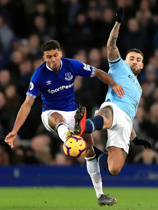 Bek Manchester City, Nicolas Otamendi berebut bola dengan pemain Everton, Dominic Calvert-Lewin selama pertandingan lanjutan Liga Inggris di Goodison Park Stadium (6/2). Hasil ini membuat City memuncaki klasemen Liga Inggris. (Peter Byrne/PA via AP)