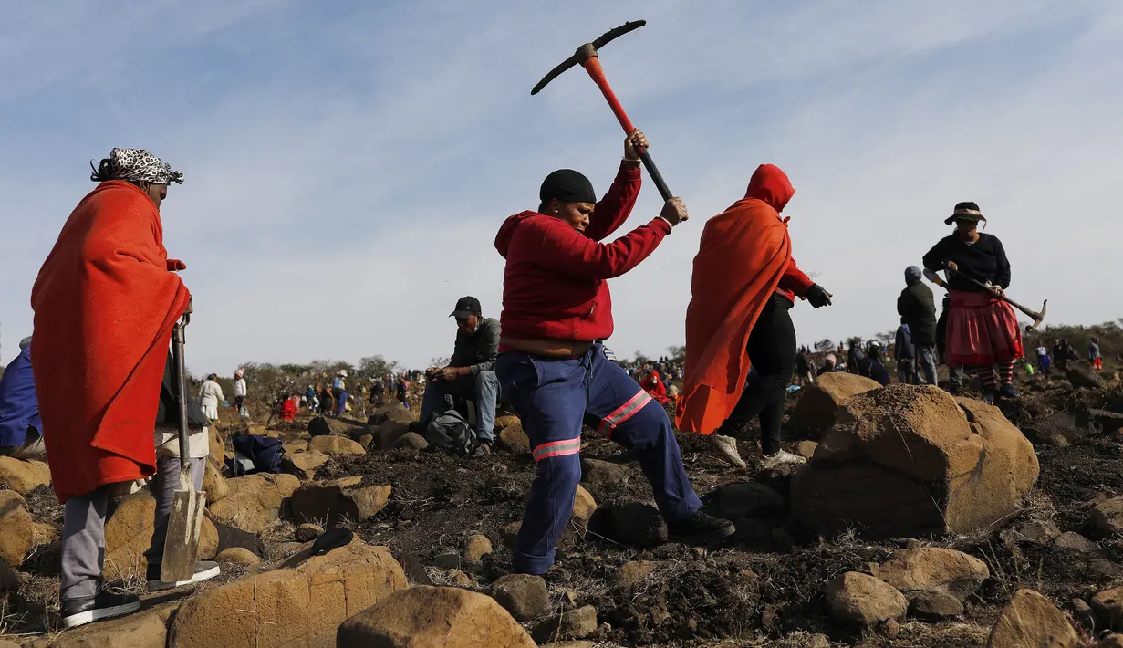 Seorang wanita menggunakan kapak saat mencari batu yang diyakini berlian di Desa KwaHlathi, luar Ladysmith, Provinsi KwaZulu-Natal, Afrika Selatan (15/6/2021). Kehebohan yang disebut-sebut sebagai 'demam berlian' ini bermula setelah penemuan batu misterius di kawasan tersebut. (AFP/Phill Magakoe)