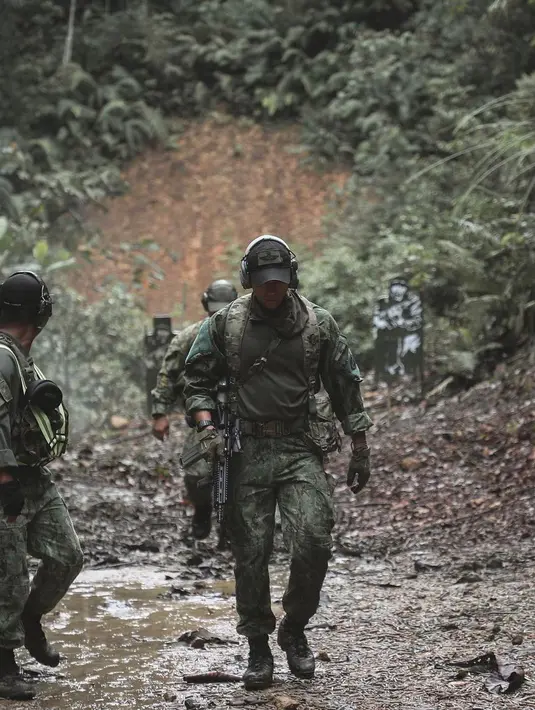 Potret Pangeran Mateen berjalan di tengah hutan dengan seragam militernya yang lengkap. Ia juga memegang senjata api laras panjang dan penutup telinga, tampak keren walau tak melihat ke arah kamera. [Foto: Instagram/tmski]