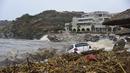 Pemandangan mobil yang terbengkalai di dekat laut setelah hujan deras di desa Agia Pelagia, di pulau Kreta, Yunani, Sabtu (15/10/2022). Dilaporkan setidaknya satu orang tewas dan lainnya hilang setelah banjir bandang yang parah. (AP Photo/Harry Nakos)