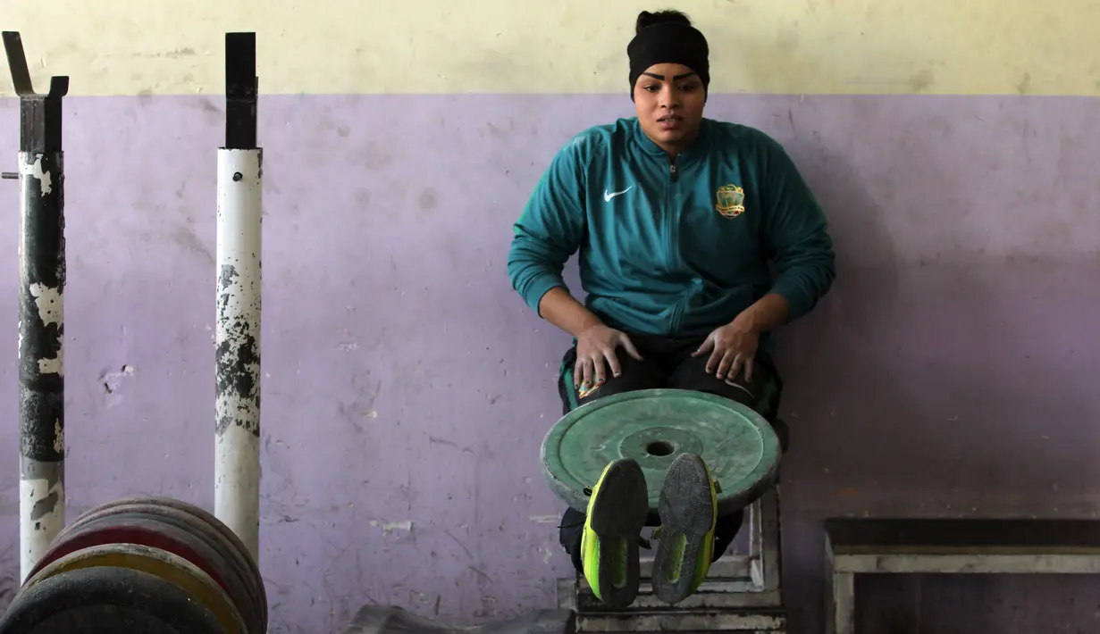 Atlet angkat besi wanita Irak Huda Salim Al-Saedi melatih kakinya dengan beban di sebuah klub di Kota Sadr, sebelah timur Baghdad, Irak (18/1). Mereka berlatih agar memenangkan pertandingan. (AFP Photo/Ahmad Al-Rubaye)