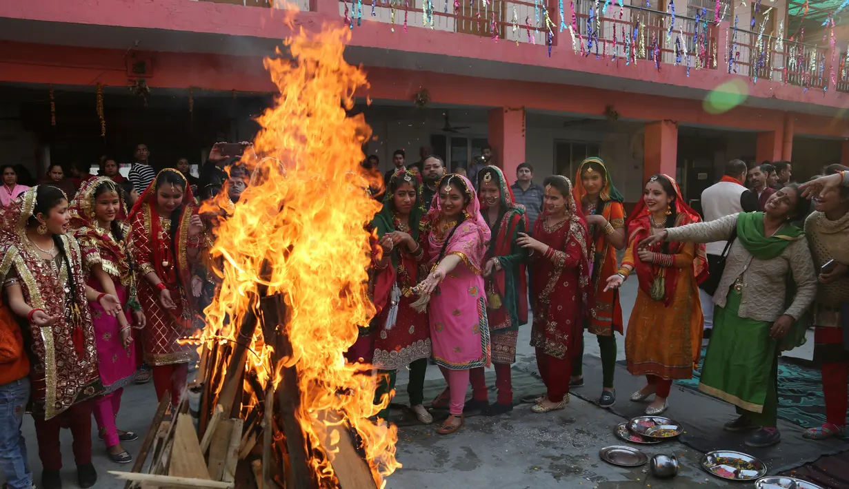 Gadis-gadis India melempar kacang ke api unggun saat mereka merayakan festival Lohri di Jammu, India 13/1). Festival Lohri ini banyak dirayakan oleh orang-orang dari wilayah Punjab di Asia Selatan. (AP Photo / Channi Anand)