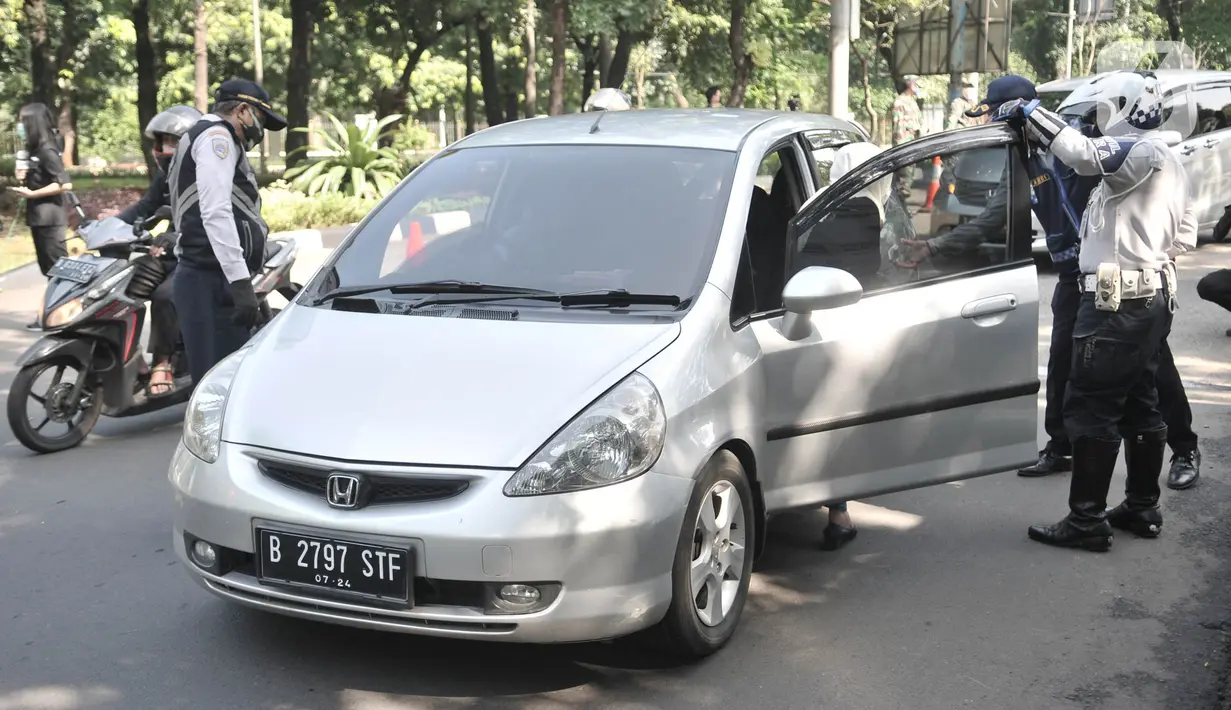 Petugas Dishub meminta penumpang mobil untuk pindah ke kursi bagian belakang saat penerapan Pembatasan Sosial Berskala Besar (PSBB) di Jalan Akses UI, Depok, Jawa Barat, Rabu (15/4/2020). PSBB di kota Depok yang resmi berlaku hari ini berlangsung selama 14 hari. (merdeka.com/Iqbal S Nugroho)