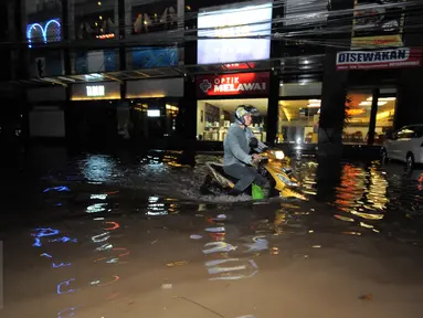Seorang pengendara motor menerobos banjir yang menggenangi kawasan Kemang, Jakarta, Minggu (25/9). Hujan deras yang mengguyur sebagian besar kawasan di Jakarta, Minggu malam, membuat wilayah Kemang terendam banjir lagi. (Liputan6.com/Helmi Afandi)