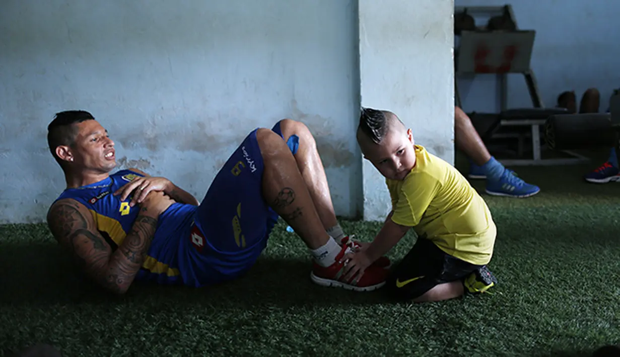 Fabio Escobar pemain Deportivo dibantu oleh anaknya yang berusia 3 tahun melakukan pemanasan.  (AP Photo/Jorge Saenz)