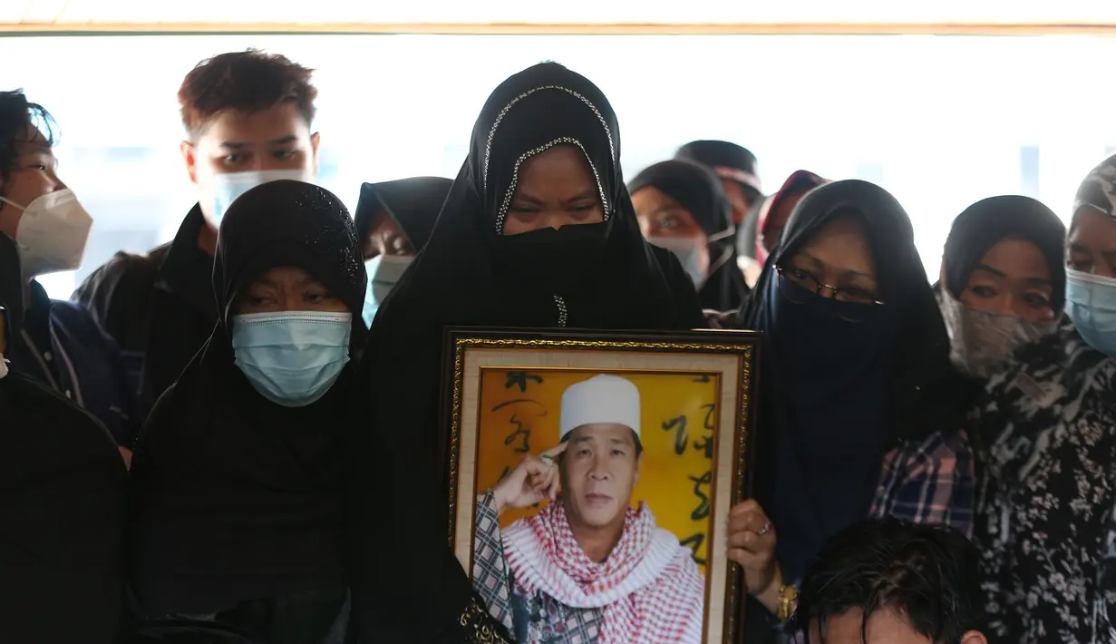 Seorang wanita membawa foto pendakwah Ramdhan Effendi atau Anton Medan saat pemakaman di area Masjid Tan Kok Liong, Pondok Rajeg, Cibinong, Bogor, Jawa Barat, Selasa (16/3/2021). Anton Medan meninggal dunia karena sakit stroke. (Kapanlagi.com/Budy Santoso)