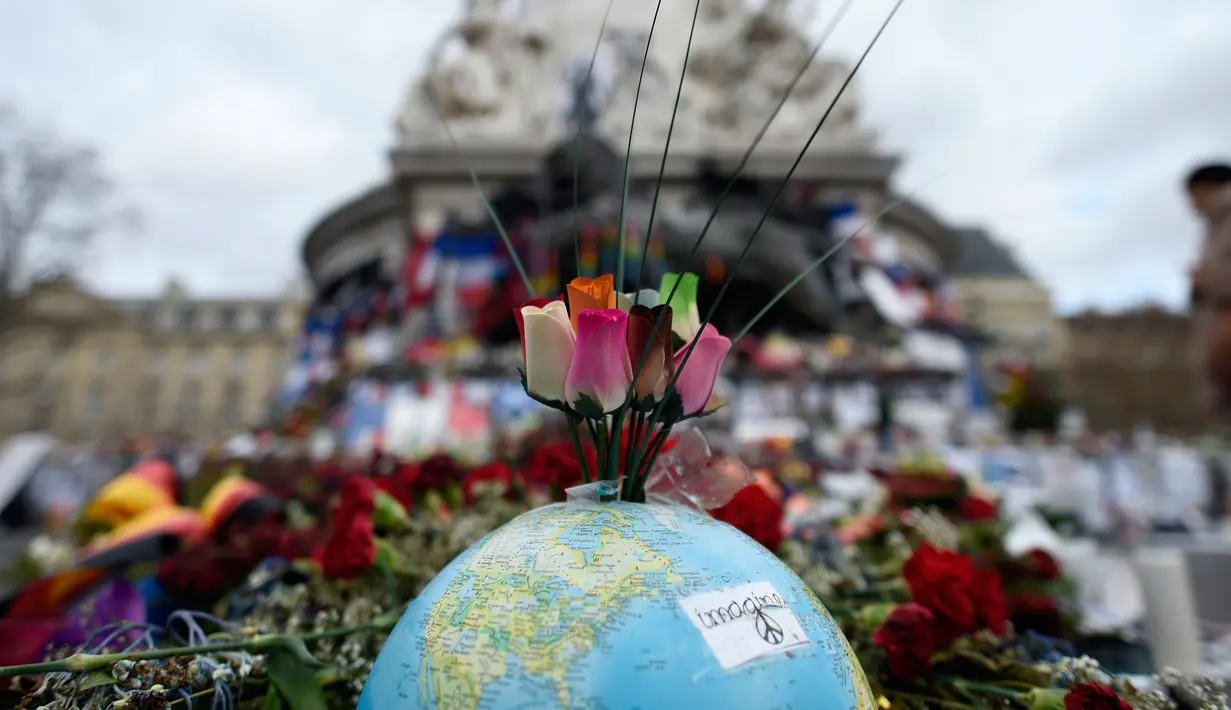 Karangan bunga di atas globe di Place de la Republique, Paris (24/12/2015). Aksi simpatik ini untuk mengenang tragedi serangan Paris yang menewaskan 130 orang. (AFP Photo/Miguel Medina)