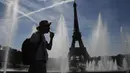 <p>Seorang pria mendinginkan diri di dekat air mancur Trocadero, di tengah suhu tinggi di Paris, Kamis (16/6/2022). Prancis akan mengalami suhu yang memecahkan rekor mendekati 40 derajat Celcius pada Juni, karena gelombang panas dini yang diperkirakan akan melanda sebagian besar negara itu. (JULIEN DE ROSA / AFP)</p>