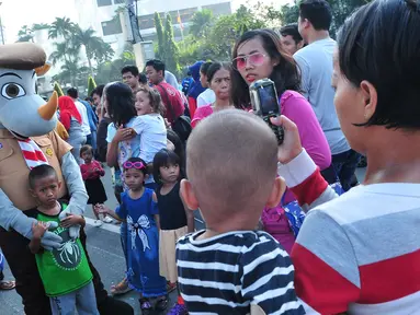 Seorang anak berfoto dengan boneka Pramuka dalam aksi Satu Indonesia di area Car Free Day (CFD), Bundaran HI, Minggu (30/7). Aksi tersebut bertajuk “Satu Nusa, Satu Bangsa, Satu Bahasa, Indonesia”. (Liputan6.com/Helmi Afandi)