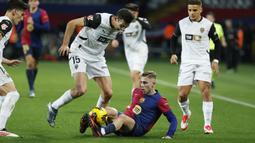 Pemain Barcelona, Fermin Lopez berebut bola dengan pemain Valencia, Cesar Tarrega pada laga lanjutan Liga Spanyol 2024/2025 di Estadi Olimpic Lluis Companys, Barcelona, Spanyol, Senin (27/01/2025) dini hari WIB. (AP Photo/Joan Monfort)