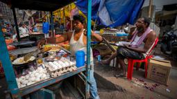 Seorang pedagang kaki lima menyiapkan makanan saat seorang pria makan di sebuah pasar grosir sayuran di Guwahati, India, Rabu (1/2/2023). Pemerintah Perdana Menteri India Narendra Modi meningkatkan belanja modal sebesar 33% untuk memacu pertumbuhan ekonomi dan menciptakan lapangan kerja menjelang pemilihan umum tahun depan. (AP Photo/Anupam Nath)