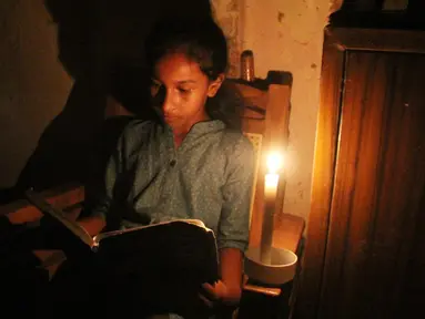 Seorang gadis membaca dengan bantuan lilin di tengah pemadaman listrik di Kolombo, Sri Lanka (17/8/2020). Sri Lanka mengalami pemadaman listrik berskala nasional pada Senin (17/8) karena kerusakan teknis di sebuah pembangkit listrik di Kerawalapitiya. (Xinhua/A. Hapuarachchi)