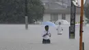 Orang-orang menyeberang jalan akibat hujan lebat di Kurume, Prefektur Fukuoka, Jepang selatan Senin, 10 Juli 2023. (Kyodo News via AP)