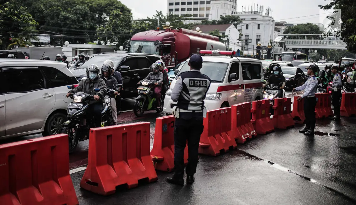 Petugas Dishub mengalihakan arus lalu lintas terkait Malam Munajat 212 di Medan Merdeka Barat dan Utara, Jakarta, Kamis (21/2). Polisi menurunkan 12 ribu personel untuk mengamankan Malam Munajat 212 di Monas. (Liputan6.com/Faizal Fanani)