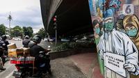 Pengendara motor menunggu lampu merah di dekat mural melawan COVID-19 di Jakarta, Kamis (17/11/2020). Sebelumnya, Presiden Joko Widodo (Jokowi) menegaskan bahwa pemerintah sangat optimistis dalam pengendalian pandemi Covid-19. (Liputan6.com/JohanTallo)