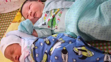 Seorang bayi laki-laki, Tran Tien Quoc (atas) sedang tidur di samping bayi laki-laki tidak dikenal di pusat kesehatan Vinh Tuong, provinsi Vinh Phuc, Minggu (15/10). Ibu asal Vietnam melahirkan bayi laki-laki itu dengan berat 7,1 kilogram. (LE PHUONG/AFP)