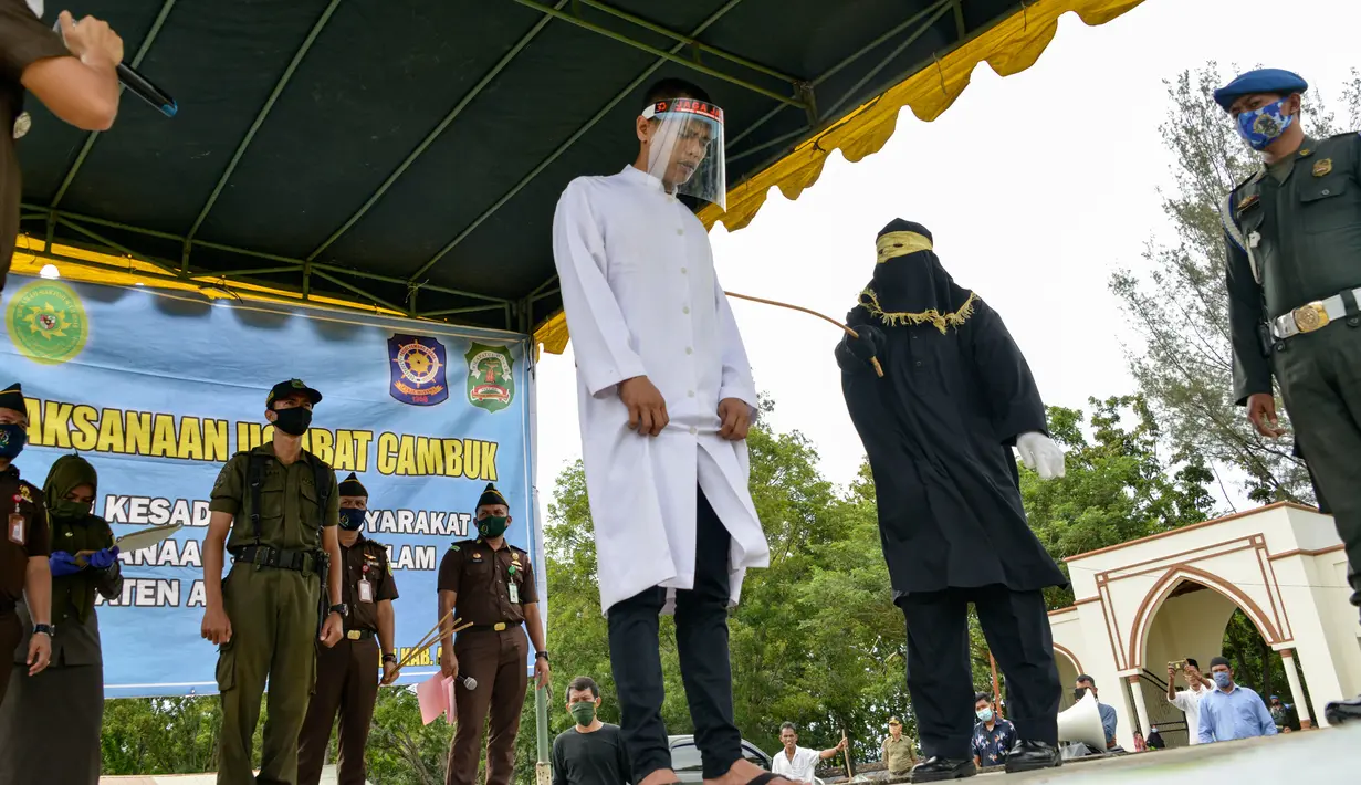 Salah seorang pasangan terpidana kasus zina (tengah) menjalani hukuman cambuk di Masjid Al Munawarah, Kota Jantho, Aceh Besar, Jumat (4/9/2020). Pasangan terpidana yang terbukti melanggar Syariat Islam dalam kasus zina itu masing masing menjalani sebanyak 100 cambuk. (CHAIDEER MAHYUDDIN/AFP)
