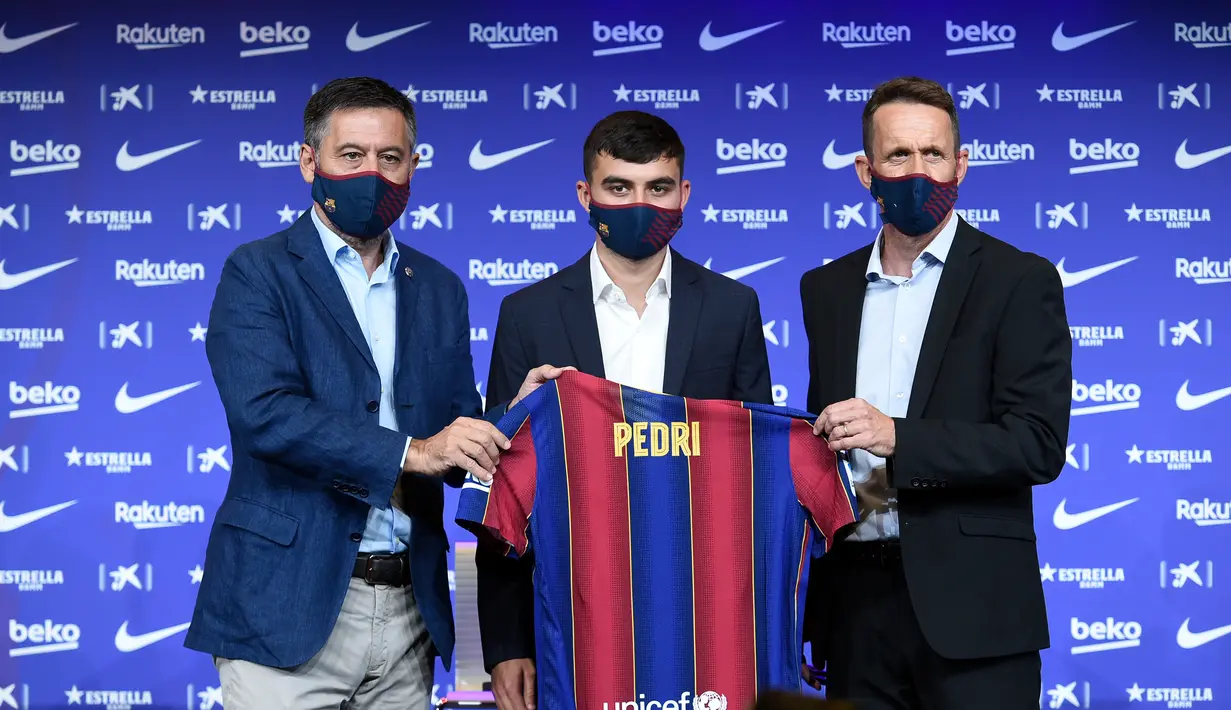 Penyerang baru Barcelona Pedri (tengah) berpose dengan jersey barunya di samping presiden klub Josep Maria Bartomeu (kiri) dan direktur olahraga Ramon Planes selama presentasi resminya di stadion Camp Nou di Barcelona (20/8/2020). Pemain 17 tahun itu diikat selama dua tahun. (AFP/Josep Lago)