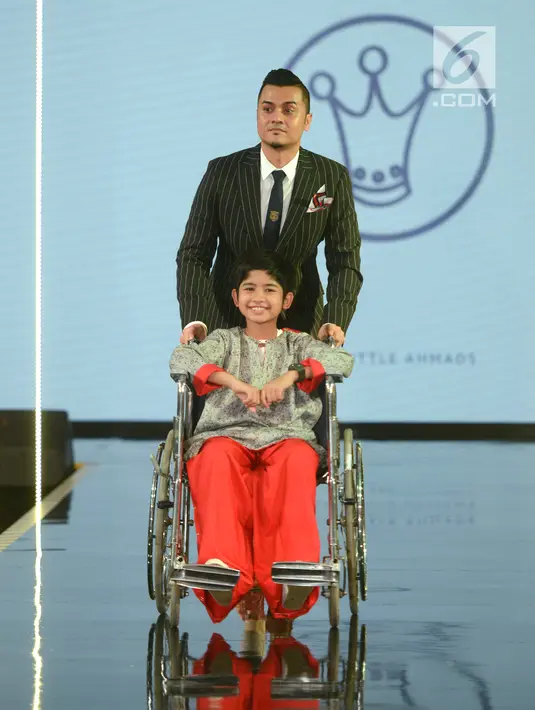 Model anak dengan kursi roda membawakan busana rancangan desainer Three Little Ahmads pada JMFW 2018 di Gandaria City, Jakarta, Sabtu (29/7). Sebanyak 21 negara dari benua Australia, Eropa, Asia dan Afrika yang tampil di JMFW. (Kapanlagi/Bayu Herdianto)